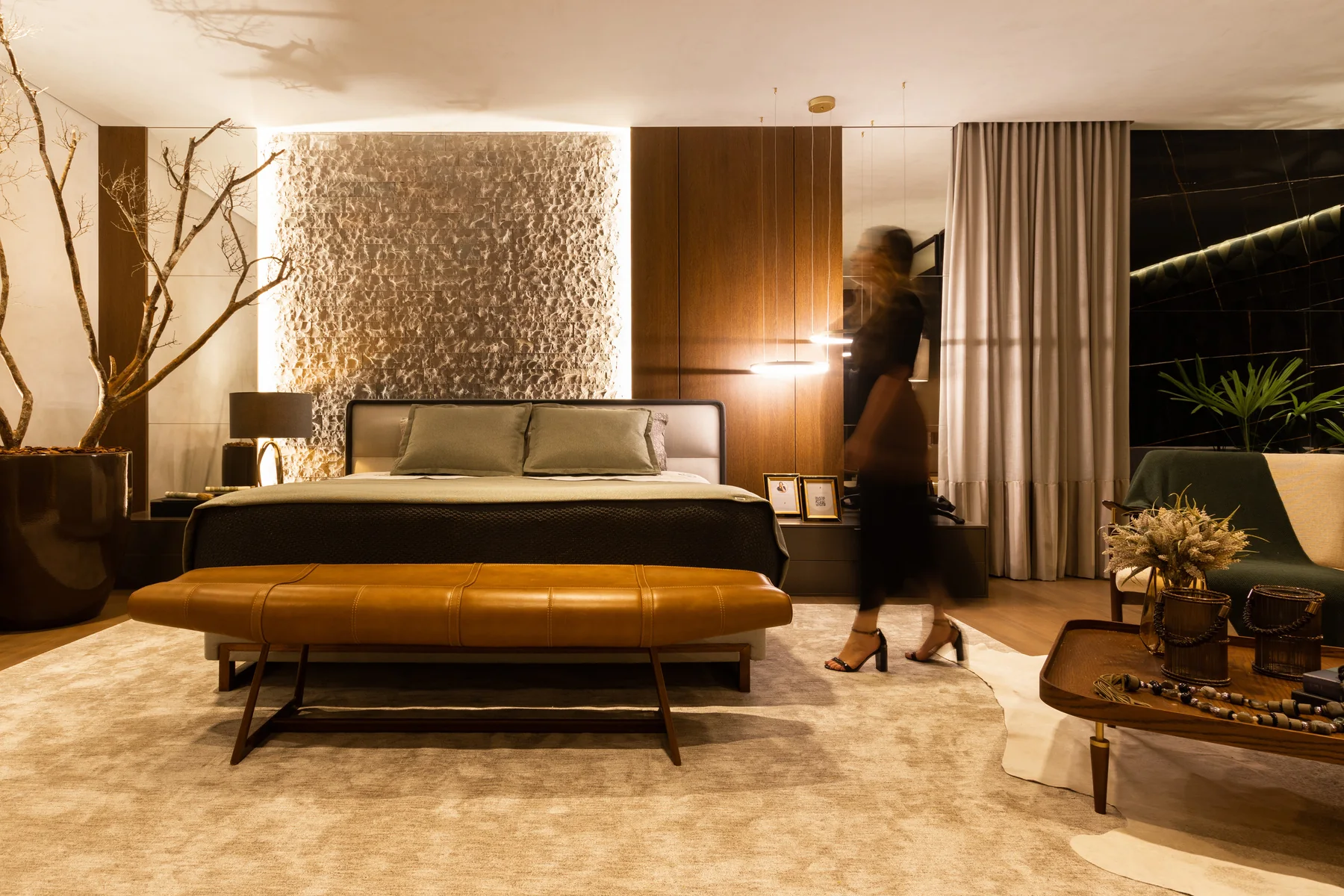 Suíte da Mostra MAI com parede texturizada iluminada, cama king e recamier de couro caramelo